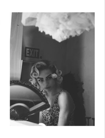 Monochrome portrait of a person with retro finger waves and a flower pinned by their eye, captured by David Sims for System Magazine.