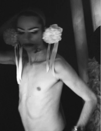 Model wearing fuzzy white earmuffs with hanging ribbons in a monochrome portrait for System Magazine.