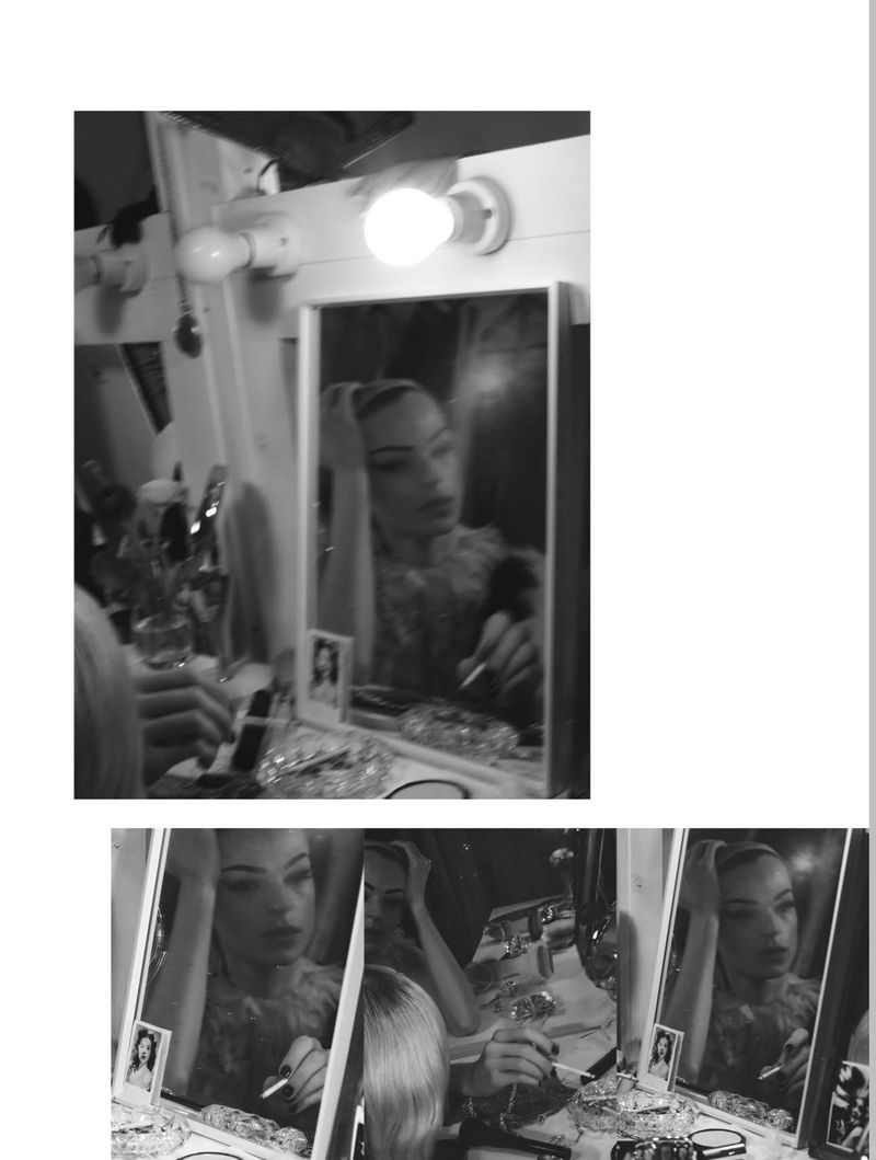 Black and white backstage editorial image of a model looking into a lit vanity mirror for System Magazine by David Sims