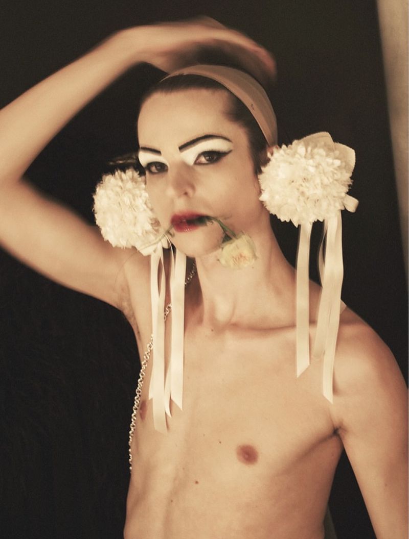 Model with dramatic white eye makeup and flower accessories holding a rose in mouth for System Magazine project