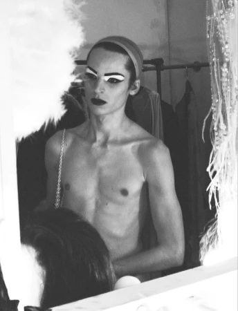 Black and white portrait of a model with dramatic stage makeup in a backstage dressing room by David Sims for System Magazine.