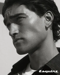 Close-up monochrome portrait of a man with dark wavy hair wearing hoop earrings and a dark collared shirt for Esquire Australia.