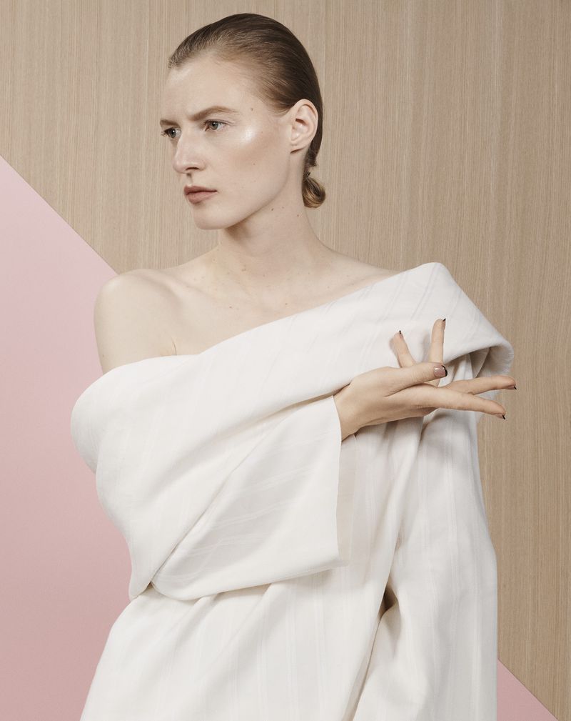 Model Julia Nobis wearing an off-the-shoulder white top against a split wood and pink background for Financial Times HTSI Magazine.