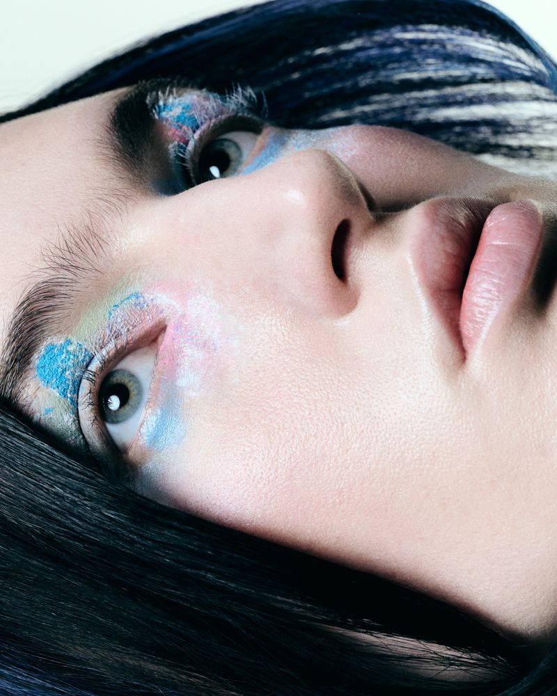 Close-up portrait of a woman with vibrant pastel eye makeup and dark hair for Tush Magazine