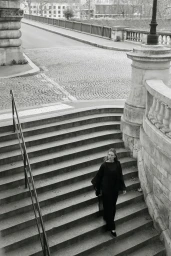 Model Liz Kennedy walking down classical stone outdoor stairs wearing a black outfit for Almada S/S 2026