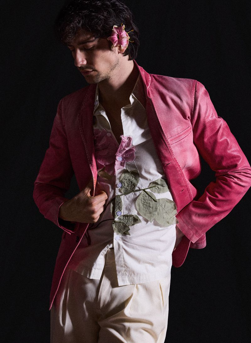 Milo Manheim wearing a pink blazer and floral shirt against a black background for V Man photographed by David Roemer