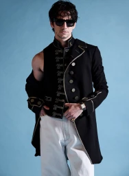 Milo Manheim in a black military jacket and white trousers against a blue background for V Man