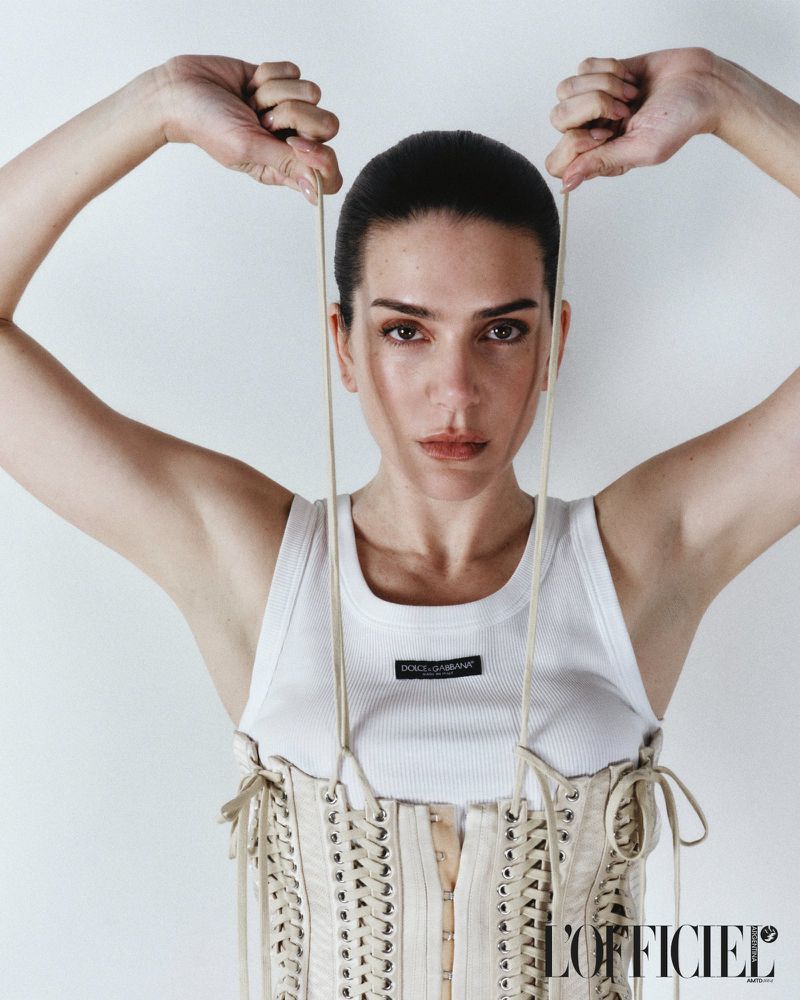 Model Valentina Ferrer wearing a white ribbed tank top and lace-up corset against a plain white background for L'Officiel Argentina.