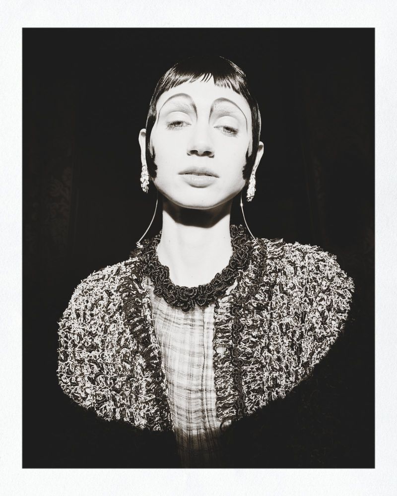 Black and white portrait of a model with sculpted dark hair and textured tweed jacket for Marie Claire Belgium Beaton Mania editorial.