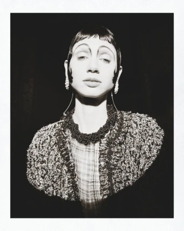 Black and white portrait of a model with sculpted dark hair and textured tweed jacket for Marie Claire Belgium Beaton Mania editorial.