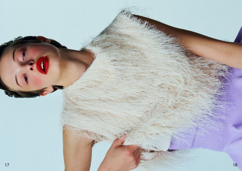 Model with red lipstick wearing a textured white fringe top against a pale background