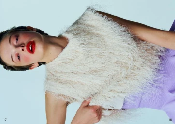 Model with red lipstick wearing a textured white fringe top against a pale background