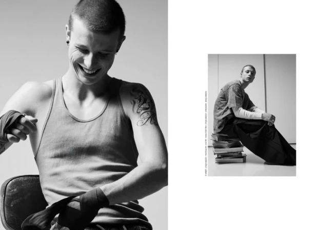 Black and white editorial portrait of actor Francesco di Tullio wrapping his hands for boxing, smiling with a tattooed arm.