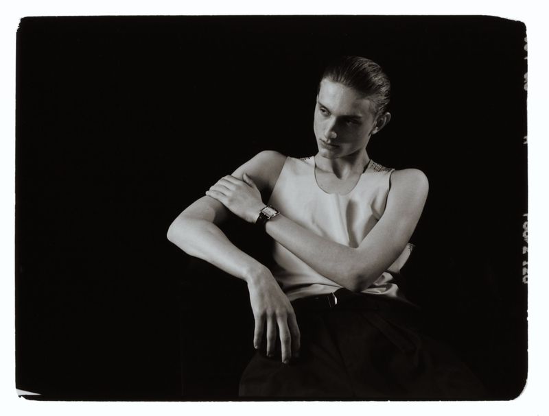 Monochrome portrait of a male model wearing a wristwatch and light tank top against a dark background