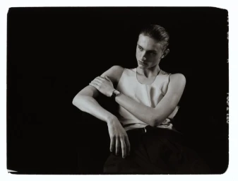 Monochrome portrait of a male model wearing a wristwatch and light tank top against a dark background
