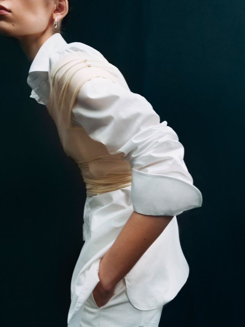 Model wearing a crisp white button-up shirt with wrapped bandeau detail against a dark background for Financial Times HTSI Magazine