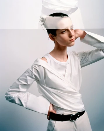 Model wearing a layered white shirt and black belt against a white seamless background with a double exposure effect.