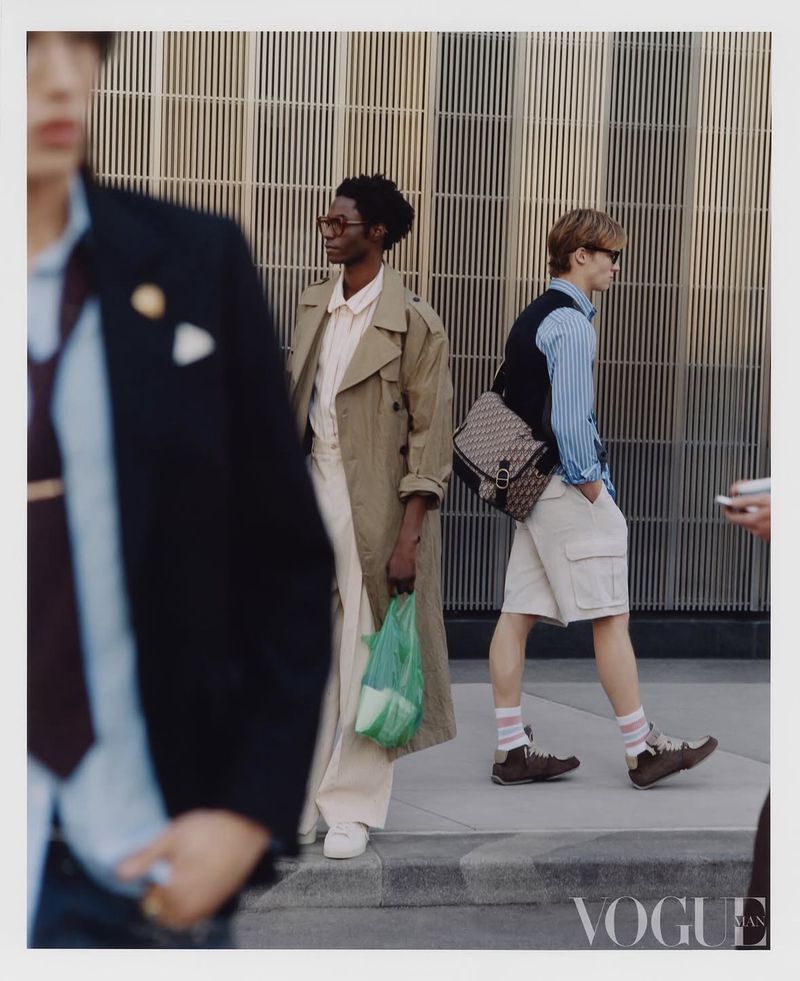 Group of male models in contemporary menswear walking past a slatted architectural wall for Vogue China Men