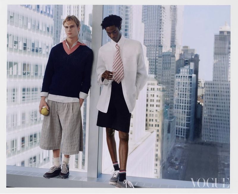 Two male models standing by a high-rise window against a city skyline for Vogue China Men