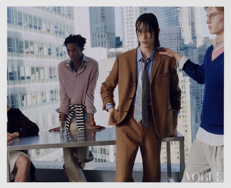 Four male models in a corporate office setting with city skyscrapers visible through large windows for Vogue China Men editorial.
