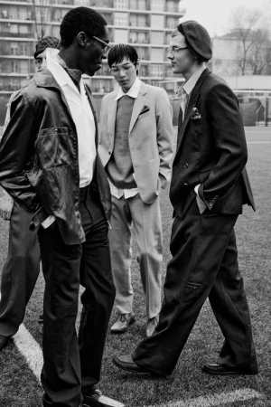 Group of four male models in tailored menswear standing on an outdoor sports field for L'Officiel Hommes Italia editorial