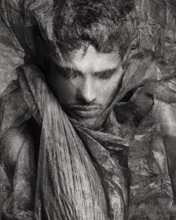 Close-up portrait of male model Jonas Barros wrapped in textured translucent material in monochrome