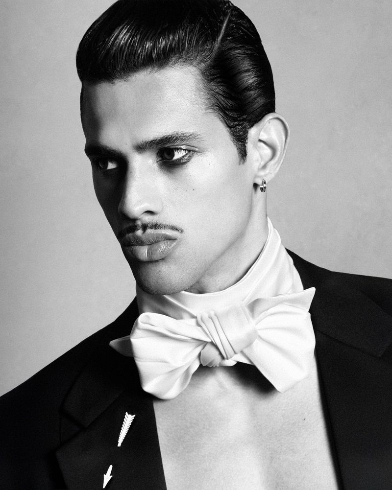 Model Jonas Barros with slicked hair and a pencil mustache wearing a black jacket and white bow tie