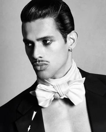 Model Jonas Barros with slicked hair and a pencil mustache wearing a black jacket and white bow tie