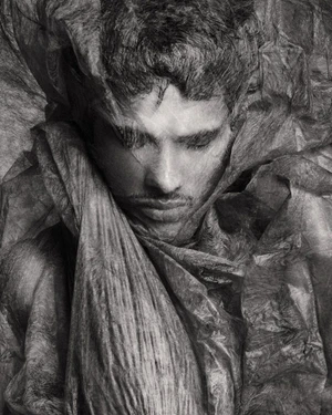 Close-up portrait of male model Jonas Barros wrapped in textured translucent material in monochrome