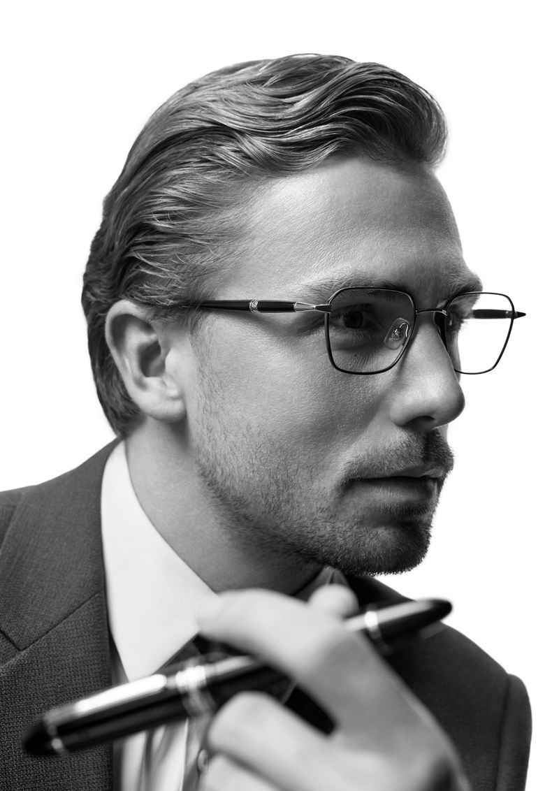 Man wearing optical glasses and suit holding a pen against a white background for the Montblanc Eyewear S/S 26 Campaign