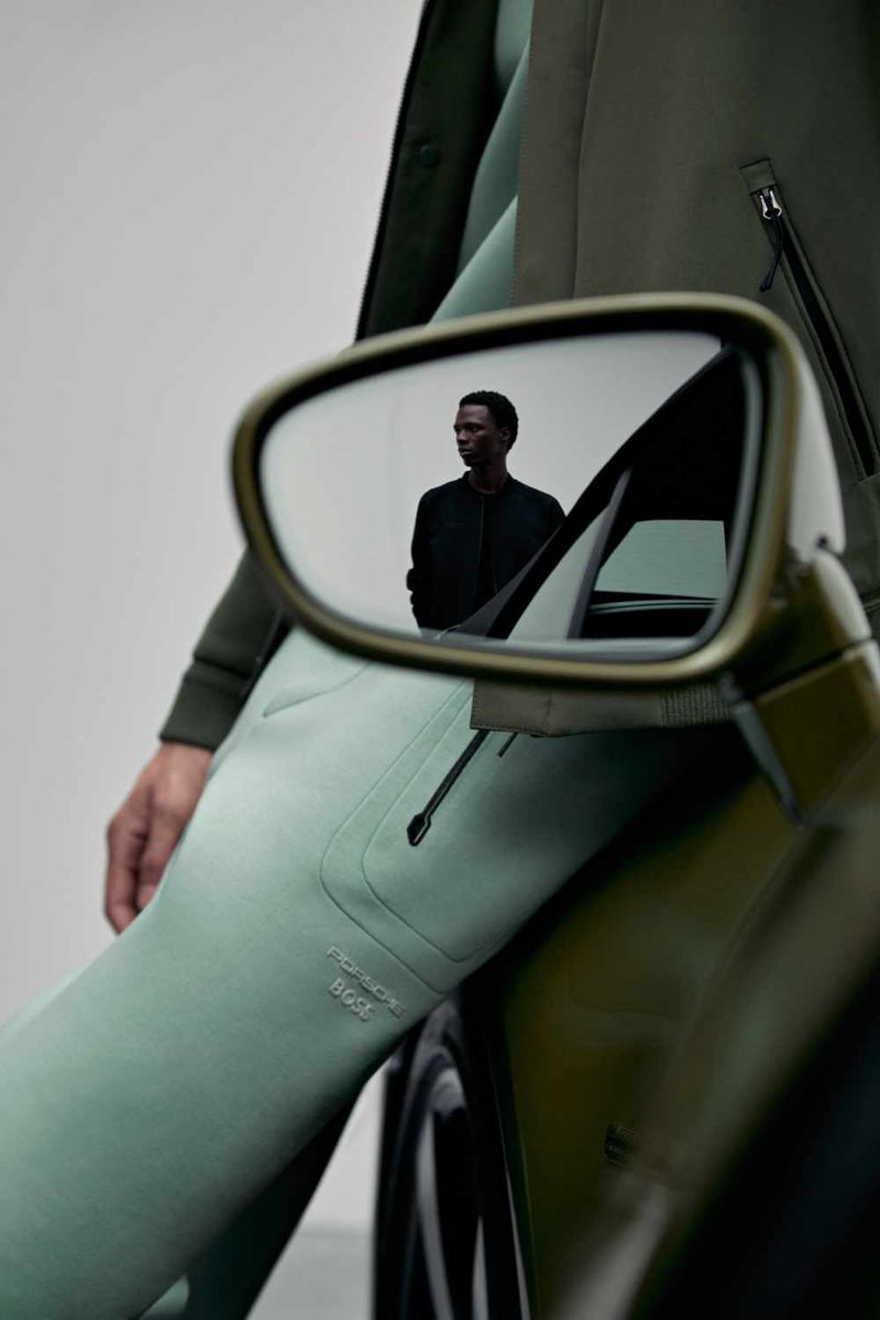 Model leaning against a luxury car with a reflection of a man in the side mirror, shot for Porsche x Boss by Vitali Gelwich.