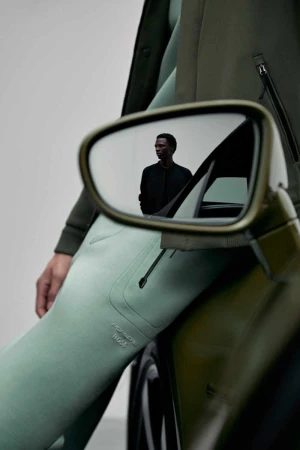 Model leaning against a luxury car with a reflection of a man in the side mirror, shot for Porsche x Boss by Vitali Gelwich.