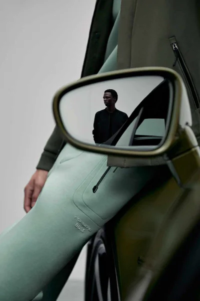 Model leaning against a luxury car with a reflection of a man in the side mirror, shot for Porsche x Boss by Vitali Gelwich.