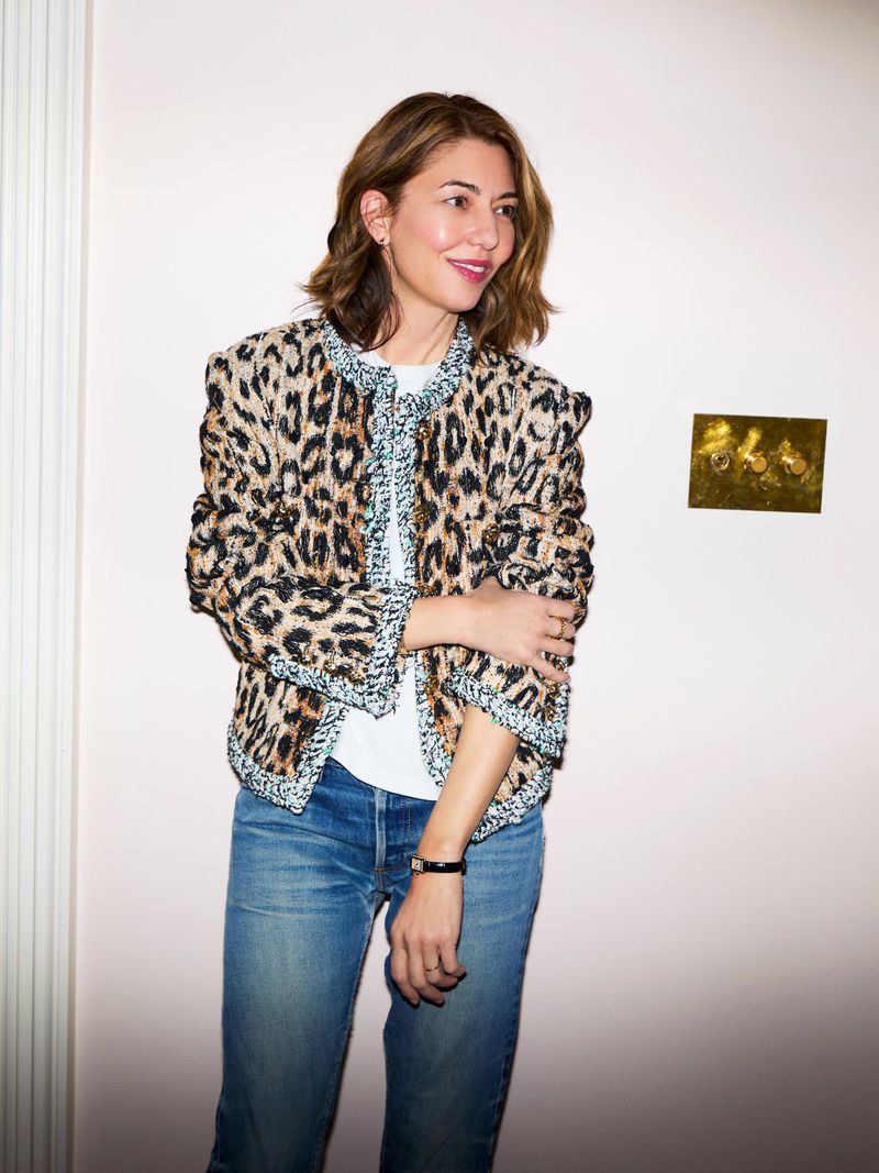 Sofia Coppola wearing a leopard print jacket and blue jeans against a pale wall for Elle U.S. captured by Carin Backoff.
