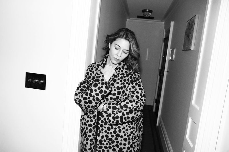 Sofia Coppola wearing a polka dot coat standing in a hallway for Elle U.S. captured by Carin Backoff