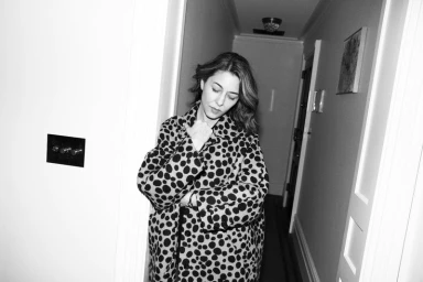 Sofia Coppola wearing a polka dot coat standing in a hallway for Elle U.S. captured by Carin Backoff