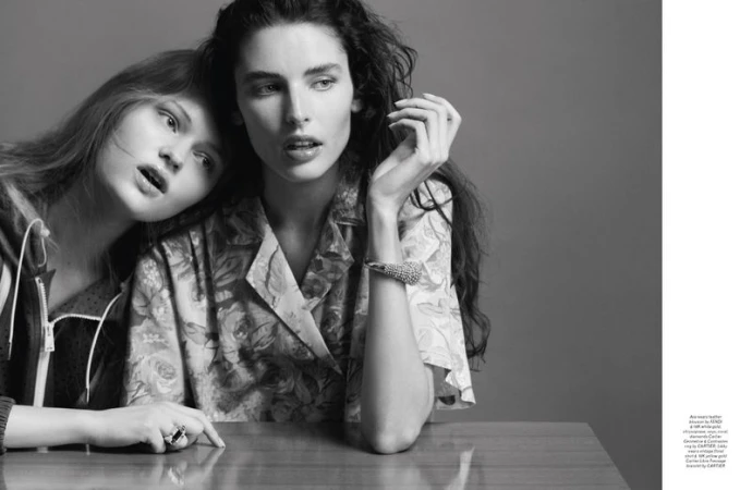 Two female models posing together in black and white for a Pop Magazine editorial shot against a grey studio backdrop.