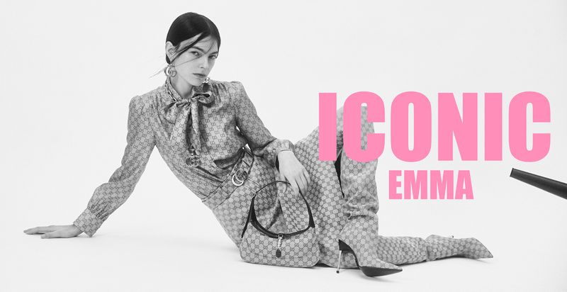 Model Emma Cabrespines seated against white background wearing patterned outfit and holding handbag