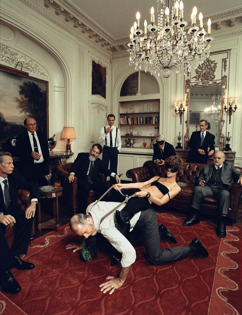Editorial scene with a woman riding a man on all fours surrounded by men in suits in a lavish living room
