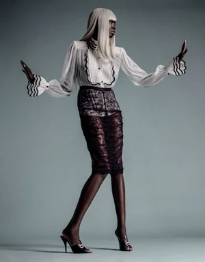 Model Ajok Madel wearing a white ruffle blouse and black lace pencil skirt against a solid grey background
