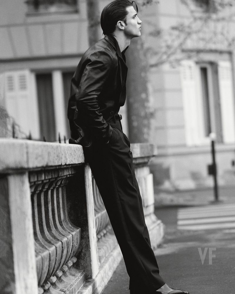 Black and white portrait of a man leaning against a stone wall on a Paris street for Vanity Fair Italia.