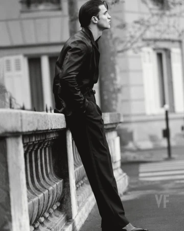 Black and white portrait of a man leaning against a stone wall on a Paris street for Vanity Fair Italia.