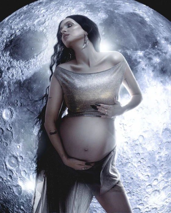 Pregnant woman with long dark hair wearing a metallic top against a detailed moon background for Kaltblut Magazine