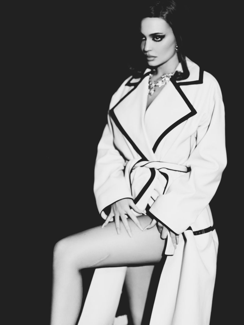 Kylie Jenner wearing a belted coat and statement necklace in a high-contrast black and white portrait for Puss Puss Magazine