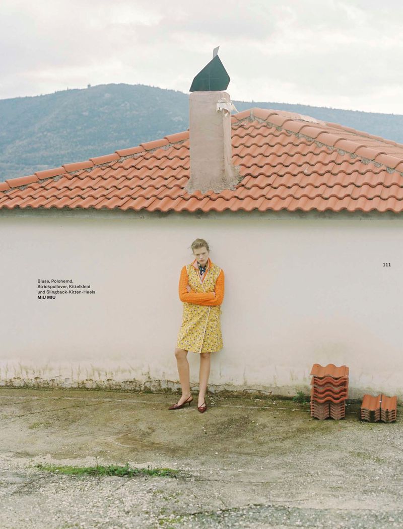 Model leaning against a white wall beneath a tiled roof for a Flair Germany fashion editorial