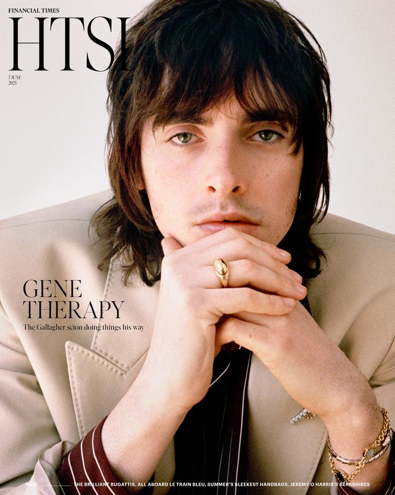 Close-up magazine cover featuring a young adult with dark hair in a beige jacket, resting hands on the face, jewelry on hands and wrist.