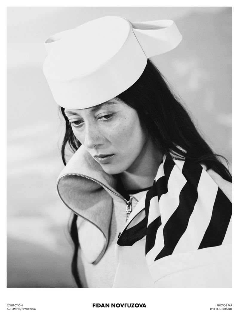Monochrome portrait of a model wearing a structured white hat and patterned scarf for Fidan Novruzova F/W 26