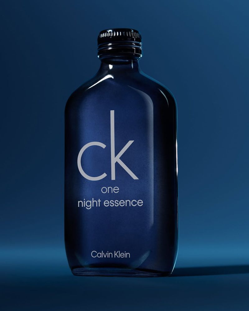 Dark blue glass perfume bottle featuring white branding typography centered against a matching blue background