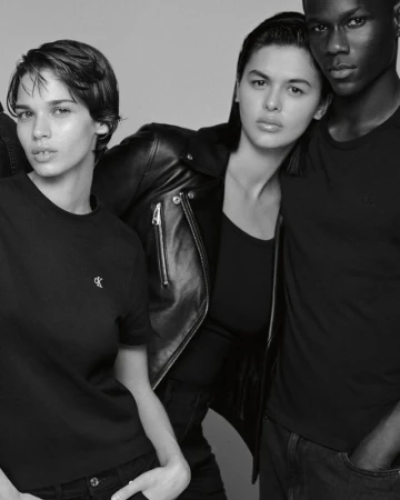 Black and white studio shot features three people modeling in casual clothing, one wearing a leather jacket, with neutral expressions.