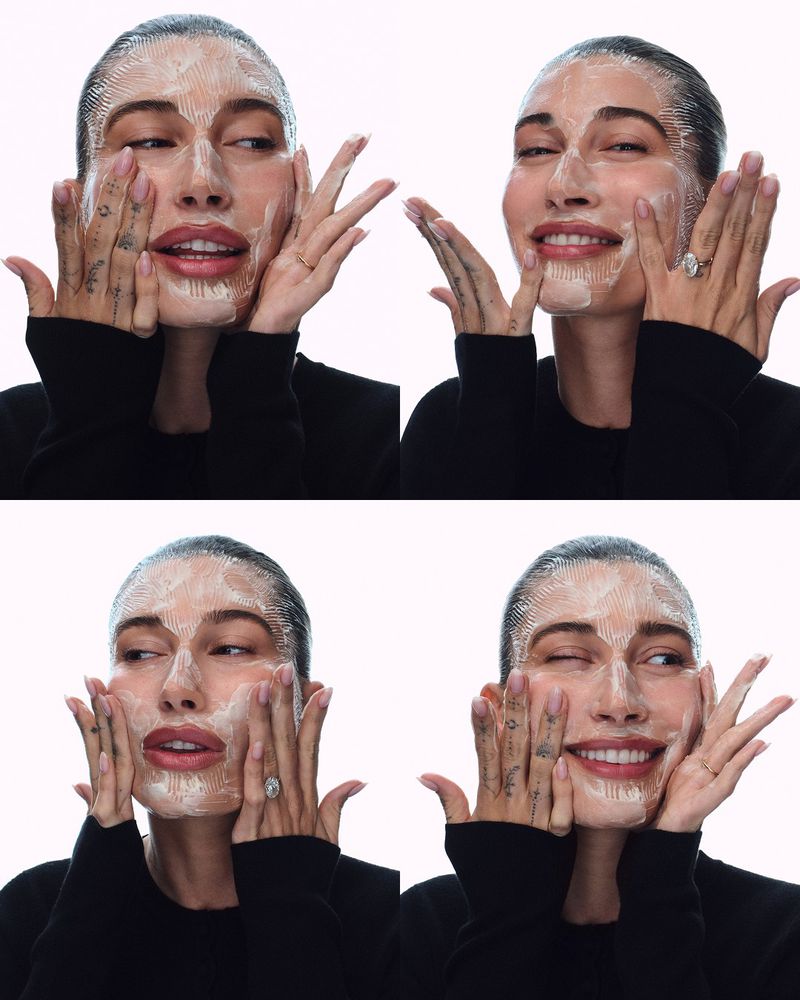 Four-panel grid of Hailey Bieber applying skincare product to her face against a bright white background.